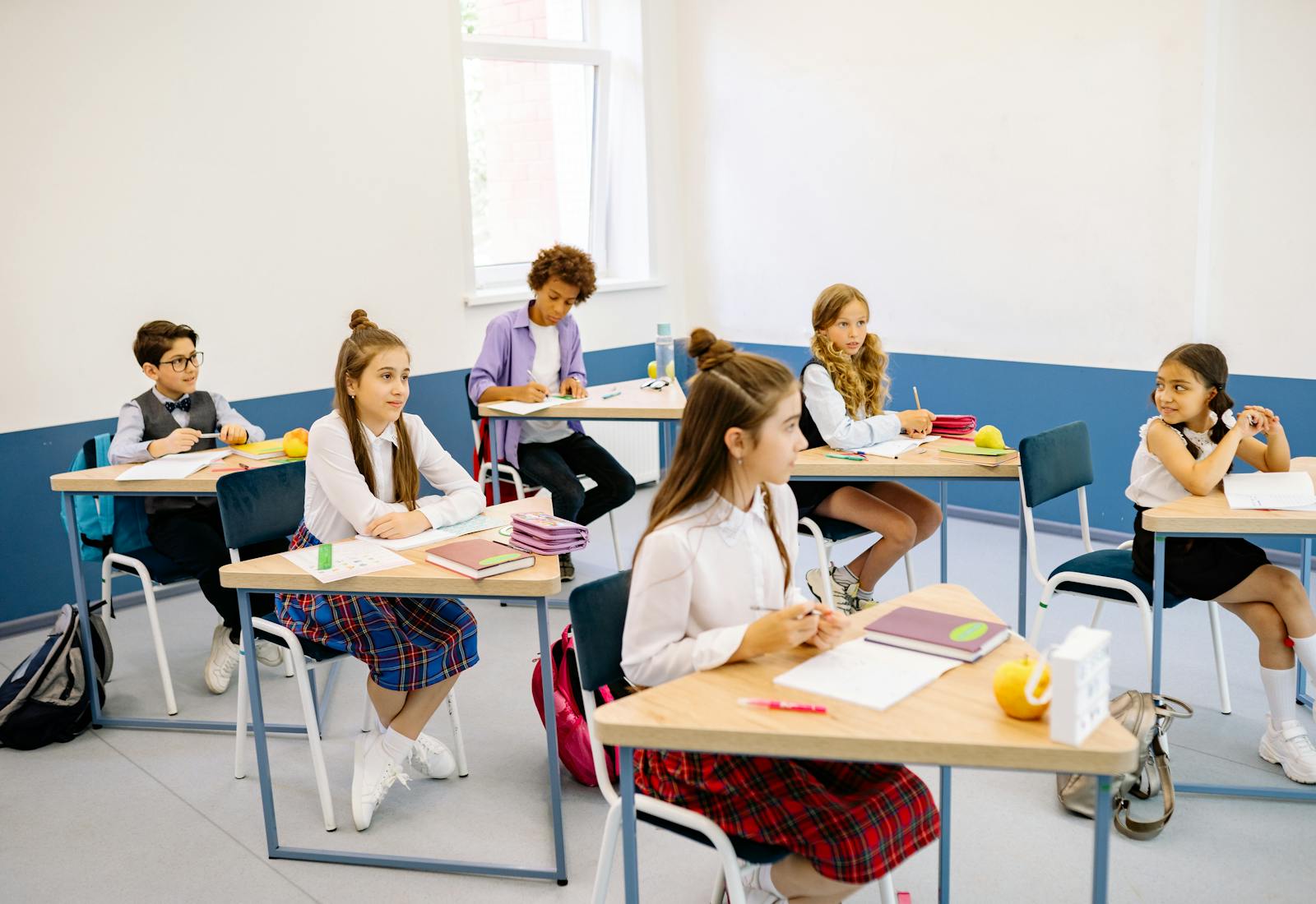 Žáci soustředěně sedí u lavic během vyučování